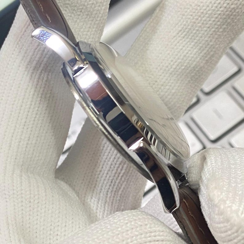 May include: A silver wristwatch with a brown leather band. The watch has a round face and a silver case.