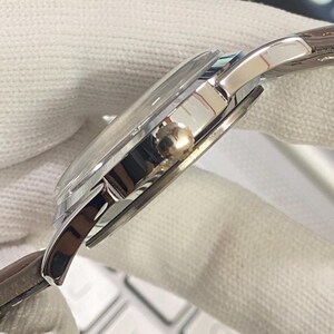 May include: A silver wristwatch with a brown leather band. The watch has a round face and a silver metal case.