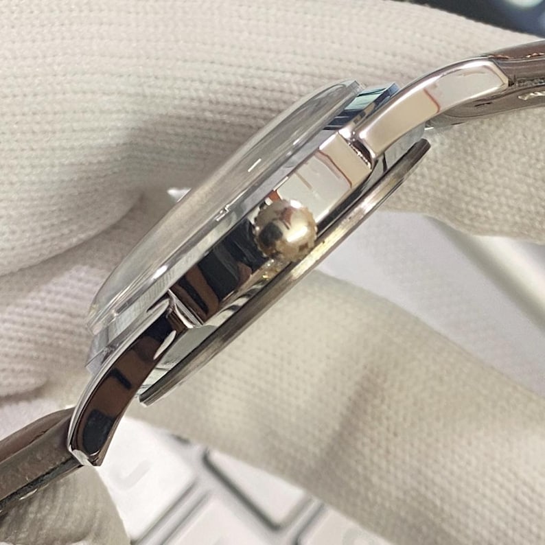 May include: A silver wristwatch with a brown leather band. The watch has a round face and a silver metal case.