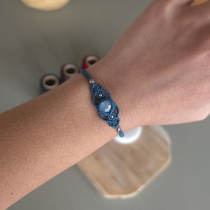Könnte beinhalten: Ein blaues Makramee-Armband mit einem hellblauen Edelstein und silbernen Perlen.