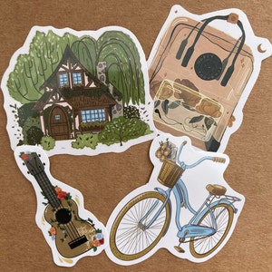 May include: Four stickers featuring a cottage with trees, a bicycle with a basket of flowers, a ukulele with floral accents, and a clear backpack with the text "Happy Thoughts".