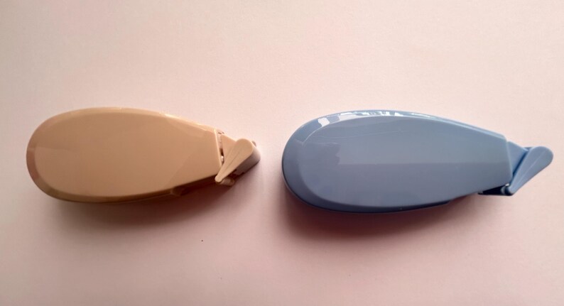 Peut inclure: Deux distributeurs de ruban adh&eacute;sif, l'un beige et l'autre bleu clair, avec un design incurv&eacute; et une petite poign&eacute;e sur le c&ocirc;t&eacute;.