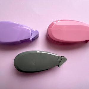 Peut inclure: Trois distributeurs de ruban adh&eacute;sif de couleurs diff&eacute;rentes&nbsp;: violet, rose et gris. Chaque distributeur est dot&eacute; d'une petite lame pointue pour couper le ruban.