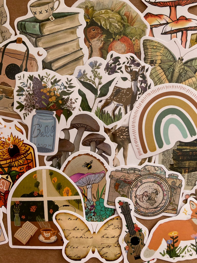 May include: A collection of colorful stickers featuring various nature-inspired designs, including mushrooms, butterflies, deer, a rainbow, a camera, a guitar, a sunflower, a mason jar, a book, and a cup of tea. The stickers are printed on white paper and have a glossy finish.