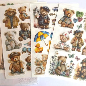 Op de afbeelding: Vellen stickers van teddyberen in aquarel. De beren zijn afgebeeld in verschillende outfits, waaronder regenjassen, hoeden en medische kleding. Andere stickers zijn vlinders, harten en bloemen. Ideaal voor scrapbooking en knutselen.