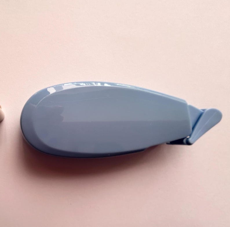 Peut inclure: Un distributeur de ruban adh&eacute;sif en plastique bleu clair avec un design incurv&eacute;. Le distributeur a une petite poign&eacute;e sur le c&ocirc;t&eacute;.
