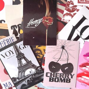 May include: A collage of various postcards and prints. The collection includes a postcard with the word "LOVE" and lips, a postcard with the words "CHERRY BOMB" and cherries, and a postcard with the Eiffel Tower.