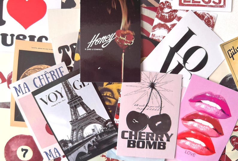May include: A collage of various postcards and prints. The collection includes a postcard with the word "LOVE" and lips, a postcard with the words "CHERRY BOMB" and cherries, and a postcard with the Eiffel Tower.