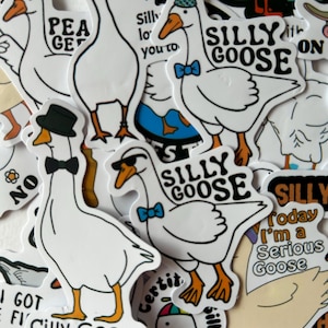 Puede incluir: Una colecci&oacute;n de pegatinas de gansos blancos con contornos negros y picos y patas naranjas. Algunos gansos llevan pajaritas, sombreros y gafas de sol. El texto en las pegatinas incluye "Silly Goose" y otras frases.