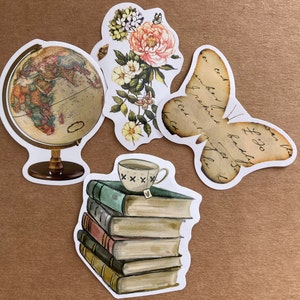 May include: A set of five vintage-style stickers featuring a globe, a butterfly, a stack of books, a teacup, and a floral design. The stickers are printed on white paper with a distressed, vintage look.