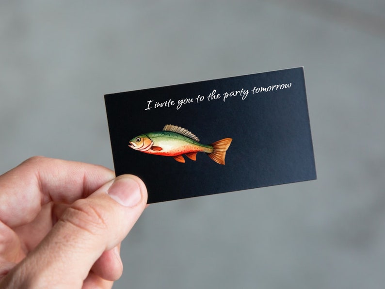 Pu&ograve; includere: Un biglietto nero con testo bianco che dice "Ti invito alla festa domani". Un'illustrazione di un pesce verde, rosso e arancione &egrave; sul biglietto.