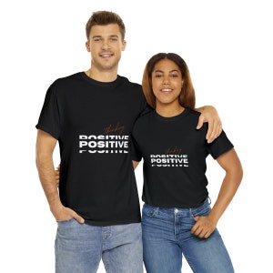 Peut inclure: Deux personnes portant des t-shirts noirs avec le texte "Thinking Positive" imprimé en blanc et marron. Le texte est empilé et décalé pour créer un effet visuel.