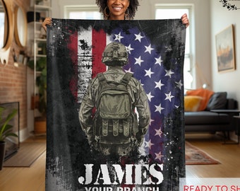May include: A black and green fleece blanket with a soldier silhouette in front of an American flag. The soldier is wearing a green military uniform and a helmet. The blanket has the text "JAMES YOUR BRANCH" at the bottom.