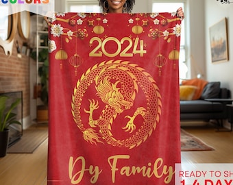 May include: Red fleece blanket with a gold dragon design and the year 2024. The blanket also has a gold inscription that says "Dy Family".
