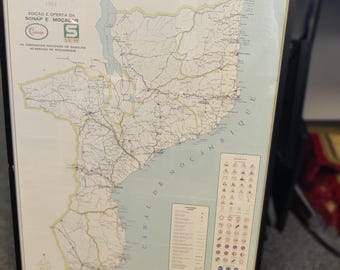 May include: Framed vintage map of Mozambique from 1964, featuring detailed road networks and geographical features. The map is in Portuguese, with text including "Mapa das estradas de MOÇAMBIQUE". The frame is black.
