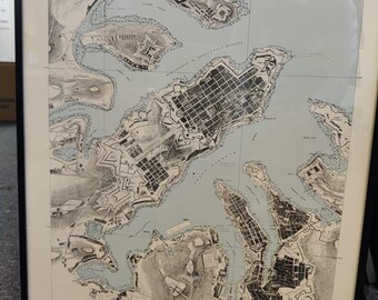 May include: Framed city plan of Valletta, Malta, featuring a detailed black and white map with light blue water areas. The map is labeled "Valletta" and "City Plan" in the upper right corner. The frame is black.