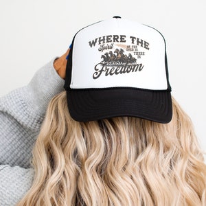 May include: Black trucker hat with a white front panel featuring a graphic of horses pulling a wagon with the text "Where the Spirit of the Lord is There is Freedom".