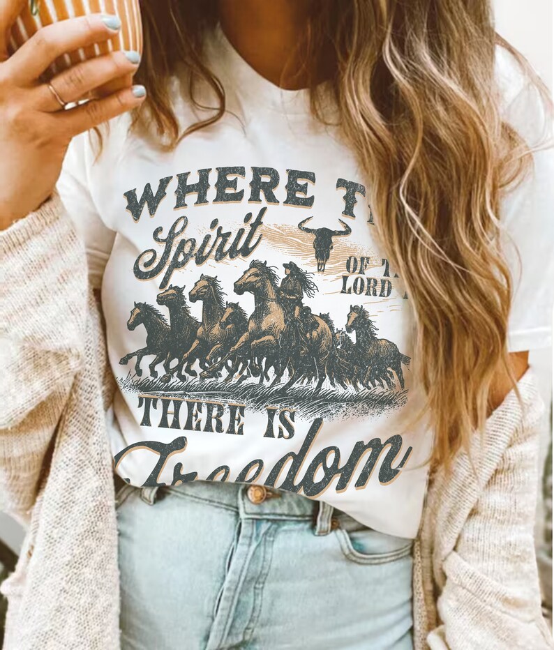 K&ouml;nnte beinhalten: Wei&szlig;es T-Shirt mit einem grafischen Druck einer Herde laufender Pferde mit dem Text "Where the Spirit of the Lord, There is Freedom".