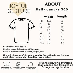 K&ouml;nnte beinhalten: Eine Schwarzwei&szlig;illustration eines T-Shirts mit dem Text "Joyful Gesture" dar&uuml;ber. Eine Gr&ouml;&szlig;entabelle f&uuml;r Bella Canvas 3001 T-Shirts wird mit Ma&szlig;en in Zentimetern f&uuml;r Breite und L&auml;nge angezeigt.