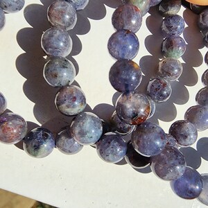 May include: A set of three bracelets made with iridescent blue and purple gemstone beads. The beads are round and have a smooth, polished finish.