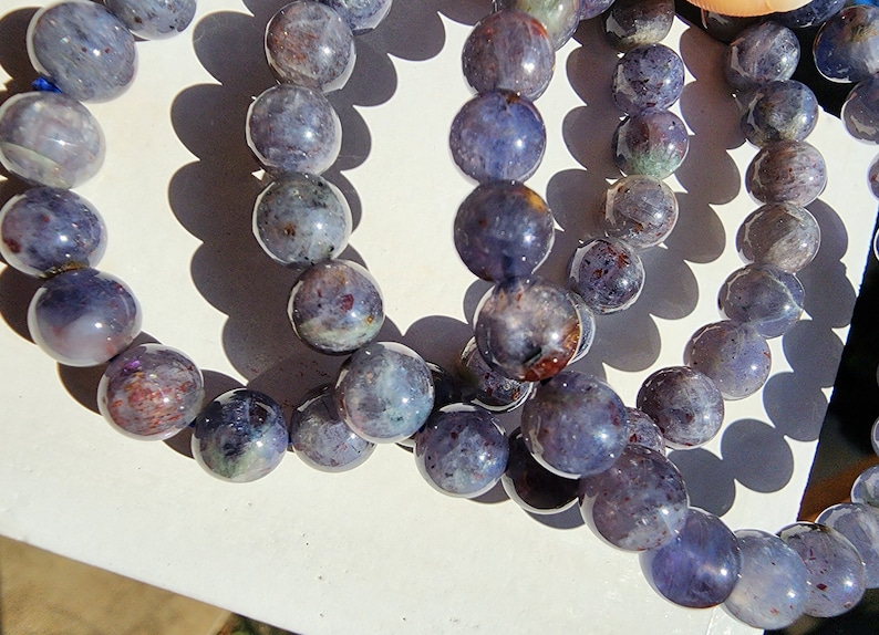 May include: A set of three bracelets made with iridescent blue and purple gemstone beads. The beads are round and have a smooth, polished finish.