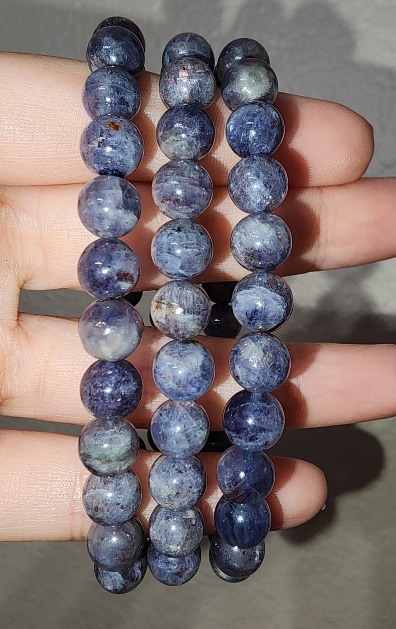 May include: Three blue and gray gemstone bracelets with round beads. The bracelets are stacked on top of each other.