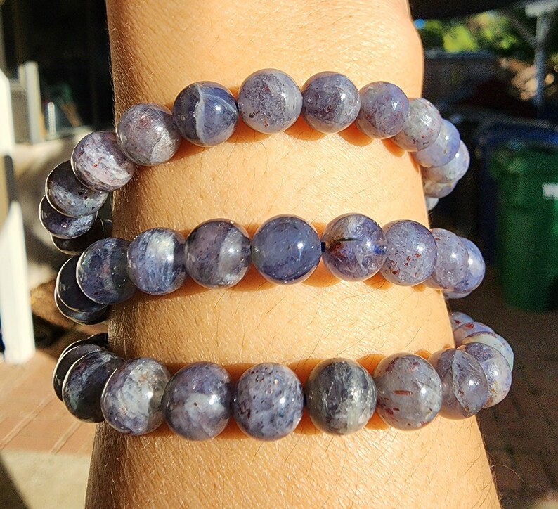 May include: Three stacked bracelets made of blue and gray gemstone beads. The beads are round and have a slightly iridescent finish.