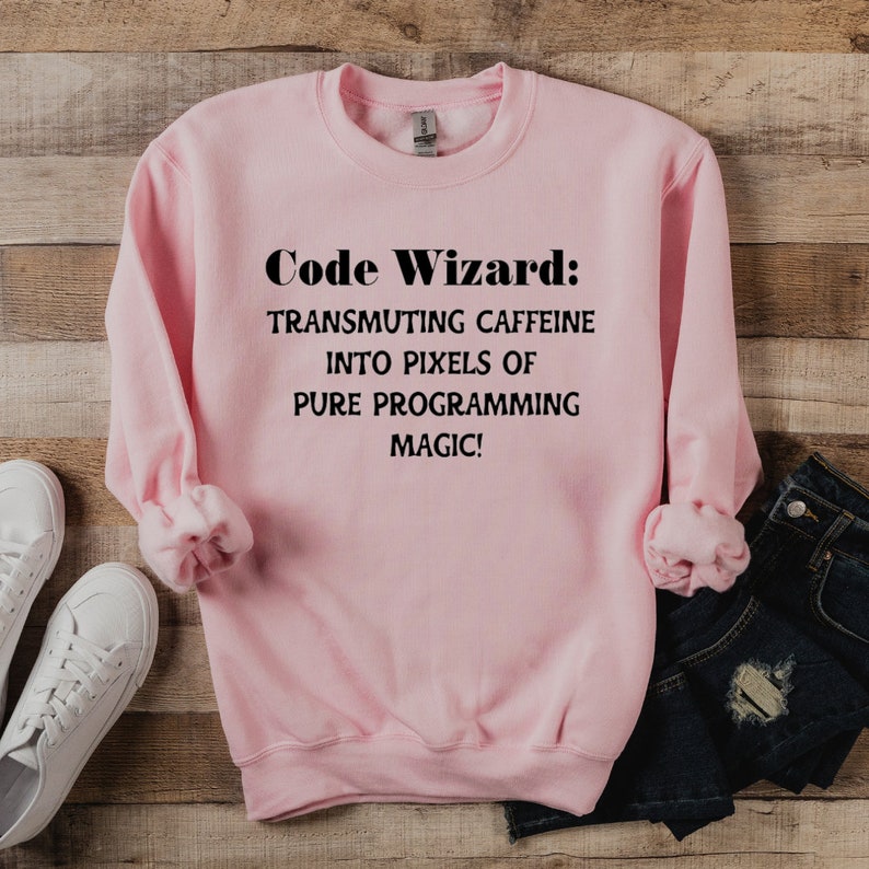 May include: Pink sweatshirt with the text "Code Wizard: Transmuting caffeine into pixels of pure programming magic!" printed in black.