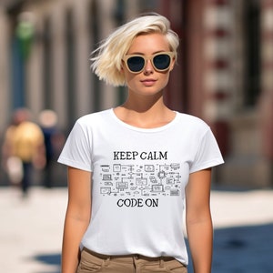 May include: White t-shirt with the text "KEEP CALM CODE ON" in black, accompanied by a schematic design of computer components. The shirt is worn by a person wearing sunglasses.
