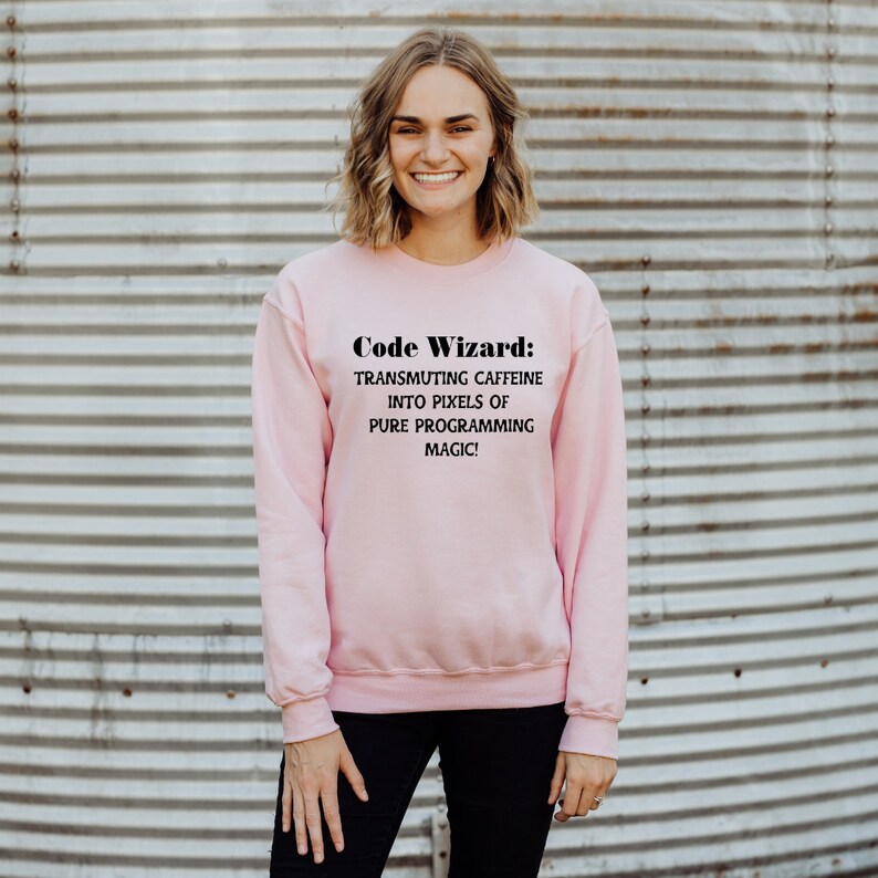 May include: A pink sweatshirt with the text "Code Wizard: Transmuting caffeine into pixels of pure programming magic!" printed on the front.