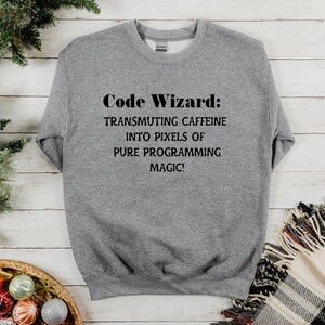 May include: Gray sweatshirt with the text "Code Wizard: Transmuting caffeine into pixels of pure programming magic!"