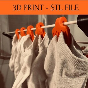 May include: Orange 3D printed sock holders hanging on a drying rack with white socks. The text "3D PRINT - STL FILE" is visible at the top of the image.
