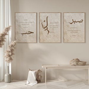 May include: Three framed prints with Arabic calligraphy and English text. The prints are on a beige background with a light brown wood frame. The text on the prints reads "Love", "Gratitude", and "Patience".