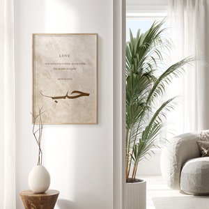 May include: A beige framed print with a brown Arabic calligraphy design and the text "LOVE" and "AND DO GOOD, INDEED ALLAH LOVES THE DOERS OF GOOD" and "QUR'AN 2:195".