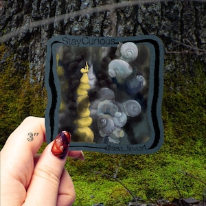 May include: A square sticker with a surreal illustration. The artwork features a yellow tower and floating snail-like forms against a dark background. The sticker is approximately 3 inches in size and has the text "Stay Curious" and "@sea_fineart".