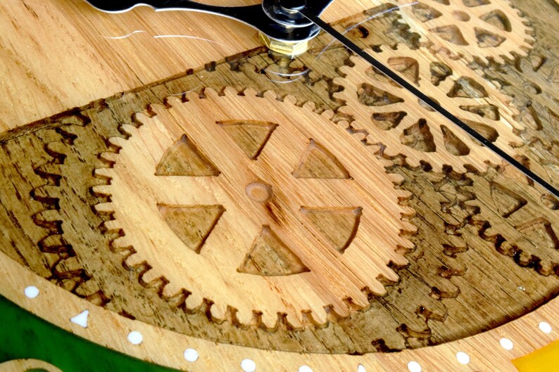 May include: Close-up of a wooden clock face with intricate gear designs. The gears are carved into the wood and have a natural brown color.