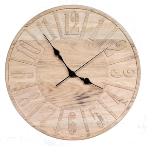 Peut inclure: Une horloge murale ronde en bois clair avec des chiffres romains gravés. Les aiguilles de l'horloge sont noires. Le cadran de l'horloge présente un motif de grain de bois naturel.