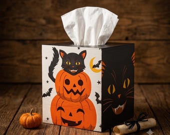 May include: A square wooden tissue box cover featuring a black cat perched on two stacked orange jack-o'-lanterns. The design includes a yellow crescent moon, small black bats, and stars on a white background, with a large black cat face on the side.