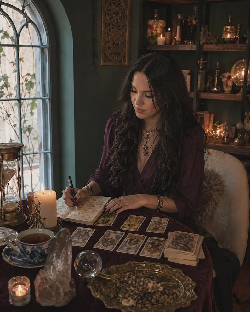 May include: A dark purple long-sleeved wrap top with a V-neckline, worn with a silver pendant necklace and beaded bracelets. The garment features a deep plum hue and a soft, draped fabric texture, providing a classic and versatile appearance.