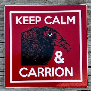 May include: A red square sign with white text and a black and white illustration of a vulture. The text reads "KEEP CALM & CARRION" in a bold, sans-serif font. The sign has a white border.