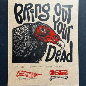 May include: A print on tan paper featuring a vulture with a red head and black feathers. The text "BRING OUT YOUR DEAD" is above the vulture. Below are a feather, a stamp, and a bone. The artist's signature is at the bottom.