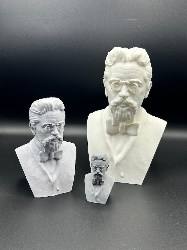 May include: Three white 3D printed busts of a man with glasses and a bow tie. The busts are different sizes, with the largest bust in the back and the smallest bust in the front.