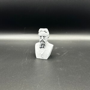 May include: A white 3D printed bust of a man with a beard and glasses wearing a bow tie.