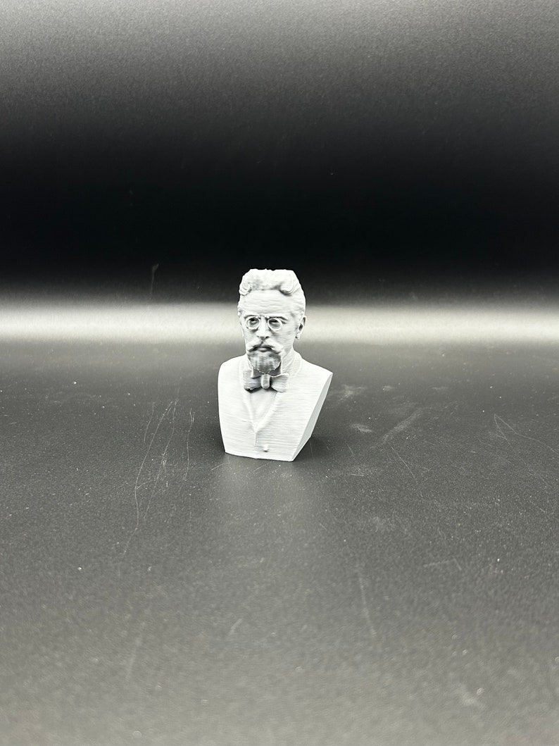 May include: A white 3D printed bust of a man with a beard and glasses wearing a bow tie.