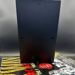 May include: A black metal stand with a hole at the top. The stand is sitting on a book with the title "The America" and the PBS logo.