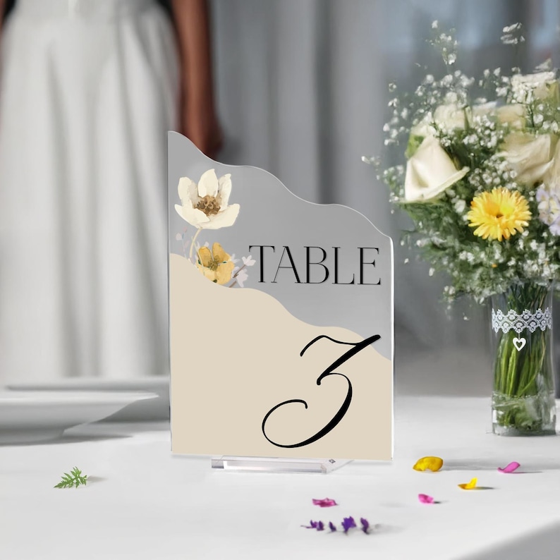 Puede incluir: Un n&uacute;mero de mesa de acr&iacute;lico blanco y beige con un dise&ntilde;o floral y el texto "TABLE 3".
