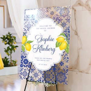 Puede incluir: Bienvenido a la despedida de soltera de Sophie Klinberg. El cartel presenta un patr&oacute;n de azulejos azules y blancos con limones y hojas verdes. La fecha de la despedida de soltera es el 23 de julio de 2024.