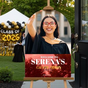 May include: A graduation party welcome sign on an easel. The sign features a photo of a smiling graduate in a cap and gown. The sign reads "Welcome to Serena's Graduation Party" with the date June 01, 2026.
