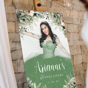 May include: A green and white floral design with a photo of a young woman in a green dress. The text "Arianna's Quincea&ntilde;era 11.06.24" is printed on the sign.