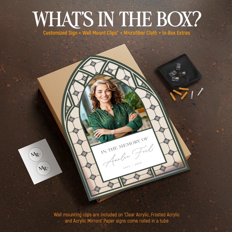 May include: A memorial sign featuring a photo of a woman, framed with a decorative green and cream design. The sign reads "In the Memory of" and includes a name and dates. The box includes wall mount clips and a microfiber cloth.
